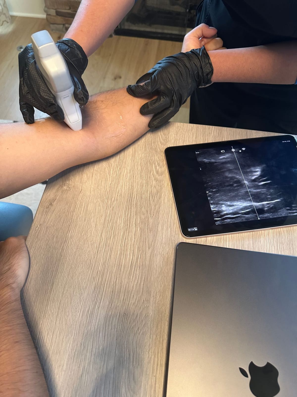 A&M IV Co. Nurse Practitioner scanning a client's forearm with a handheld ultrasound, with the live vein image on a tablet